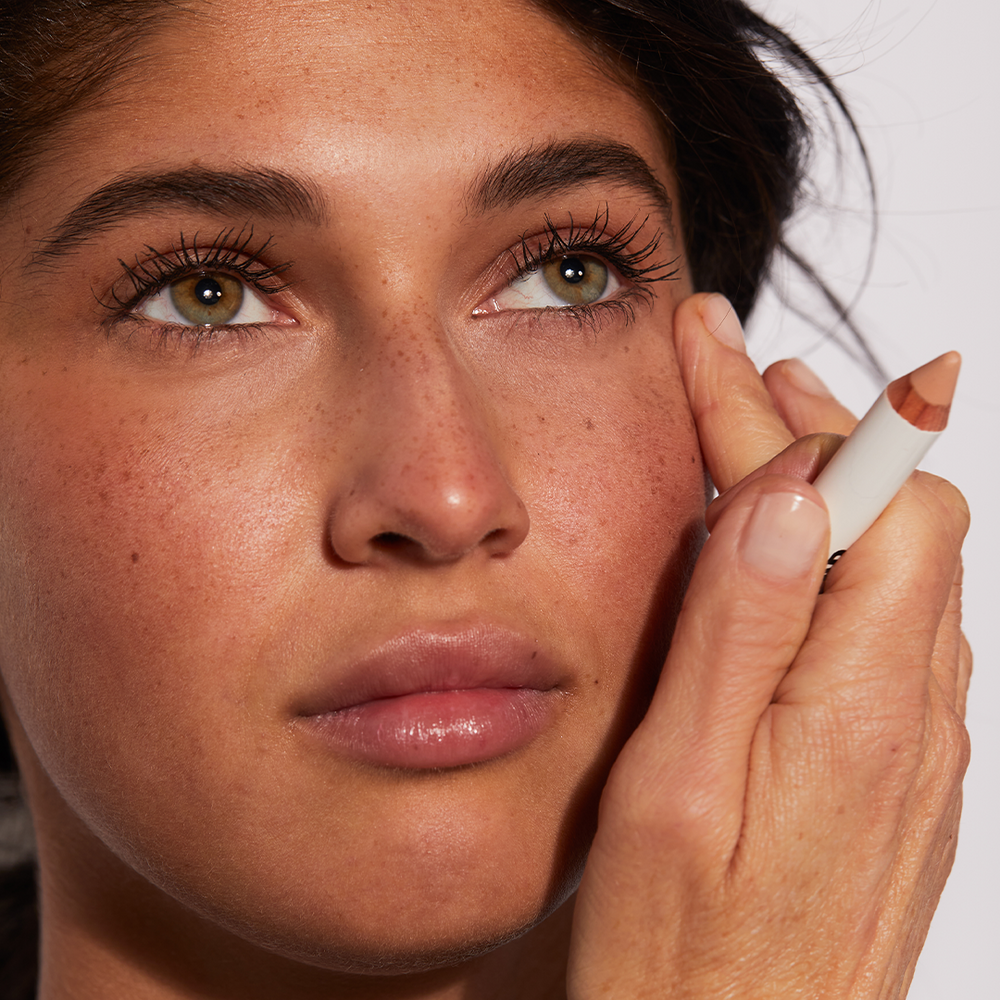 A woman using Jones Road Beauty's The Face Pencil
