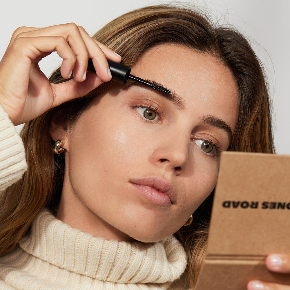 A woman applying Jones Road Beauty's The Brow Gel to her eyebrows