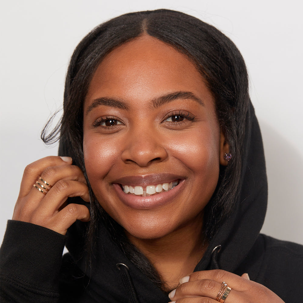 A smiling woman wearing Jones Road Beauty's Shimmer Face Oil in Cool Rose