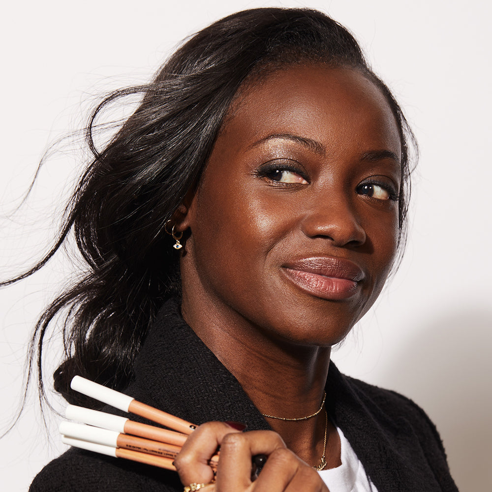 A woman holding several of Jones Road Beauty's The Best Pencils