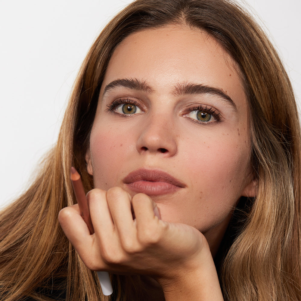 A model holding up The Lip Pencil by Jones Road Beauty